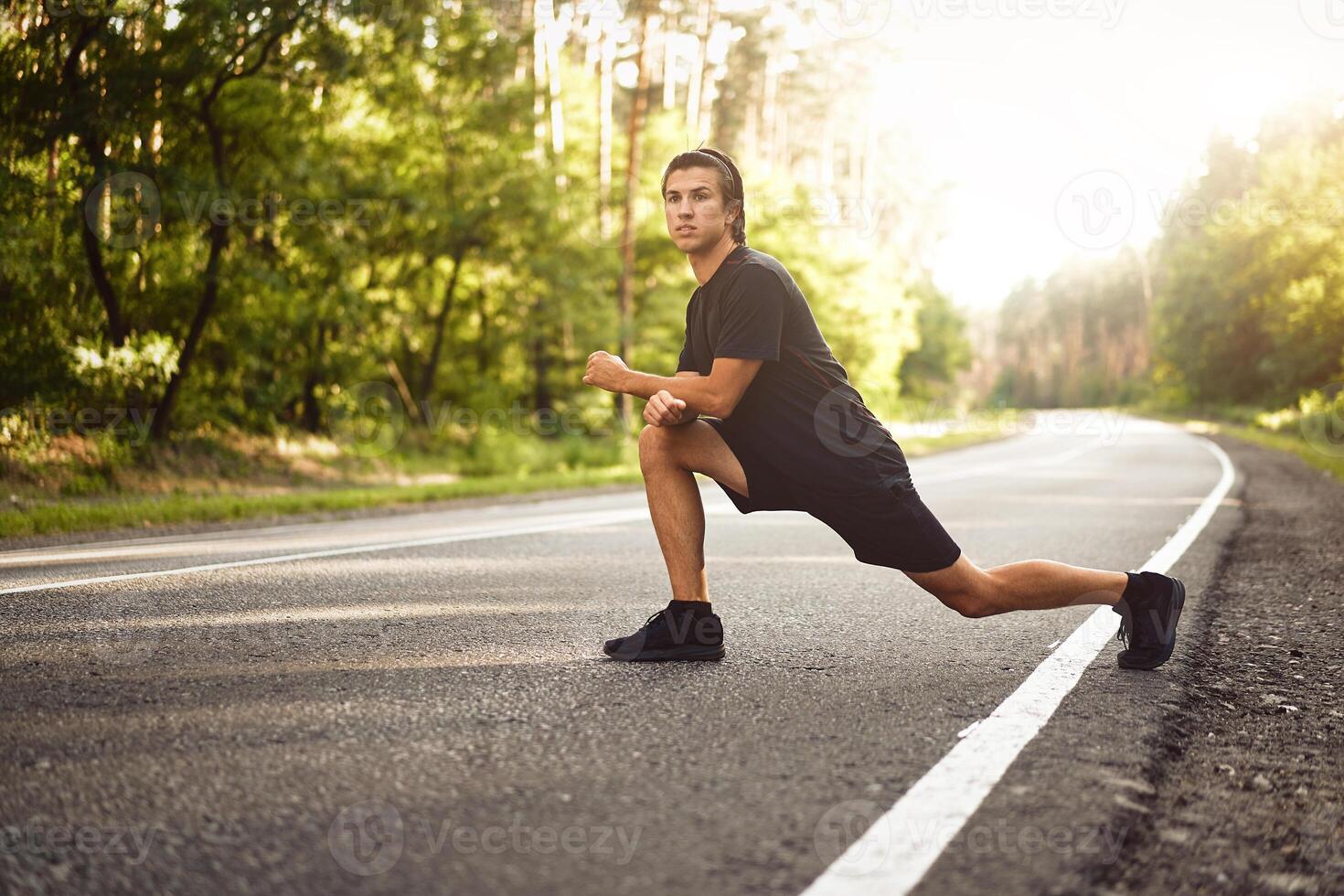 Middle age man warming up at forest road before jogging. Men stretching for running exercises. Handsome 30s athlet doing fitness outdoor photo