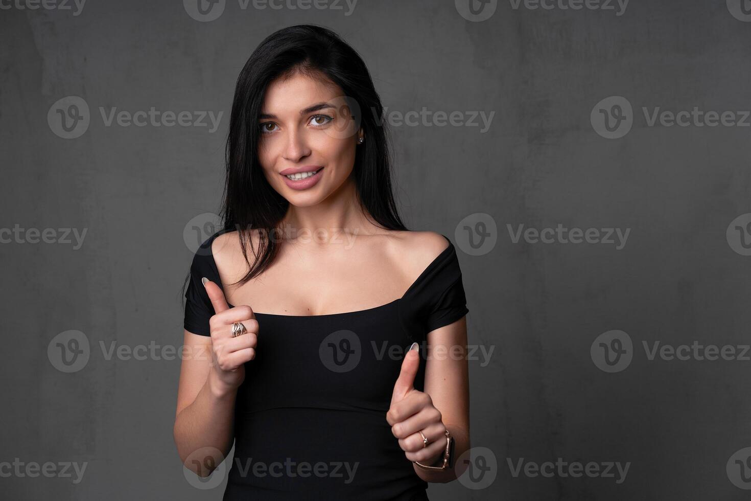 Young beautiful caucasian girl showing thumbs up on two hands stand studio against a dark background. photo