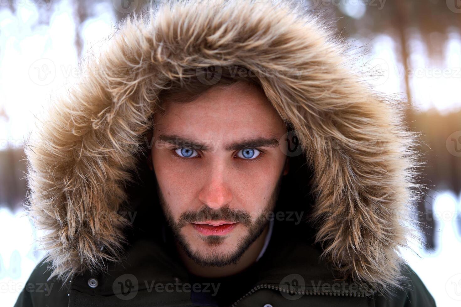 Attractive bearded man standing outdoors in winter season forest. photo