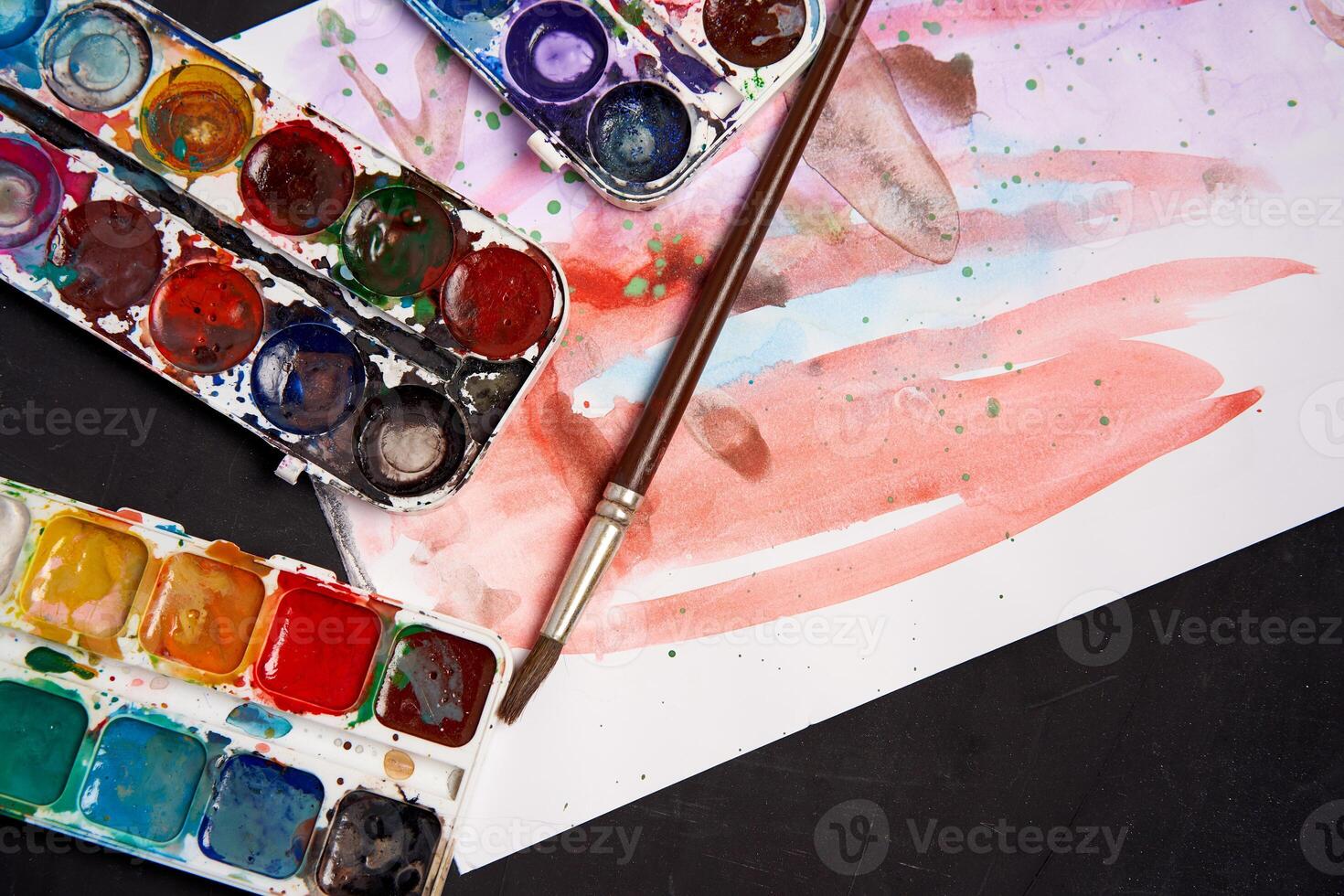 Set of watercolor paints on a black background. Brushes drawing. Creative background. School for teaching drawing. photo