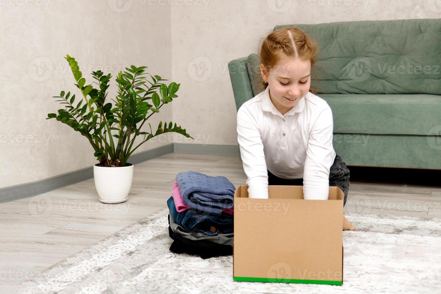 cute girl collects clothes in a box for charity and donation photo