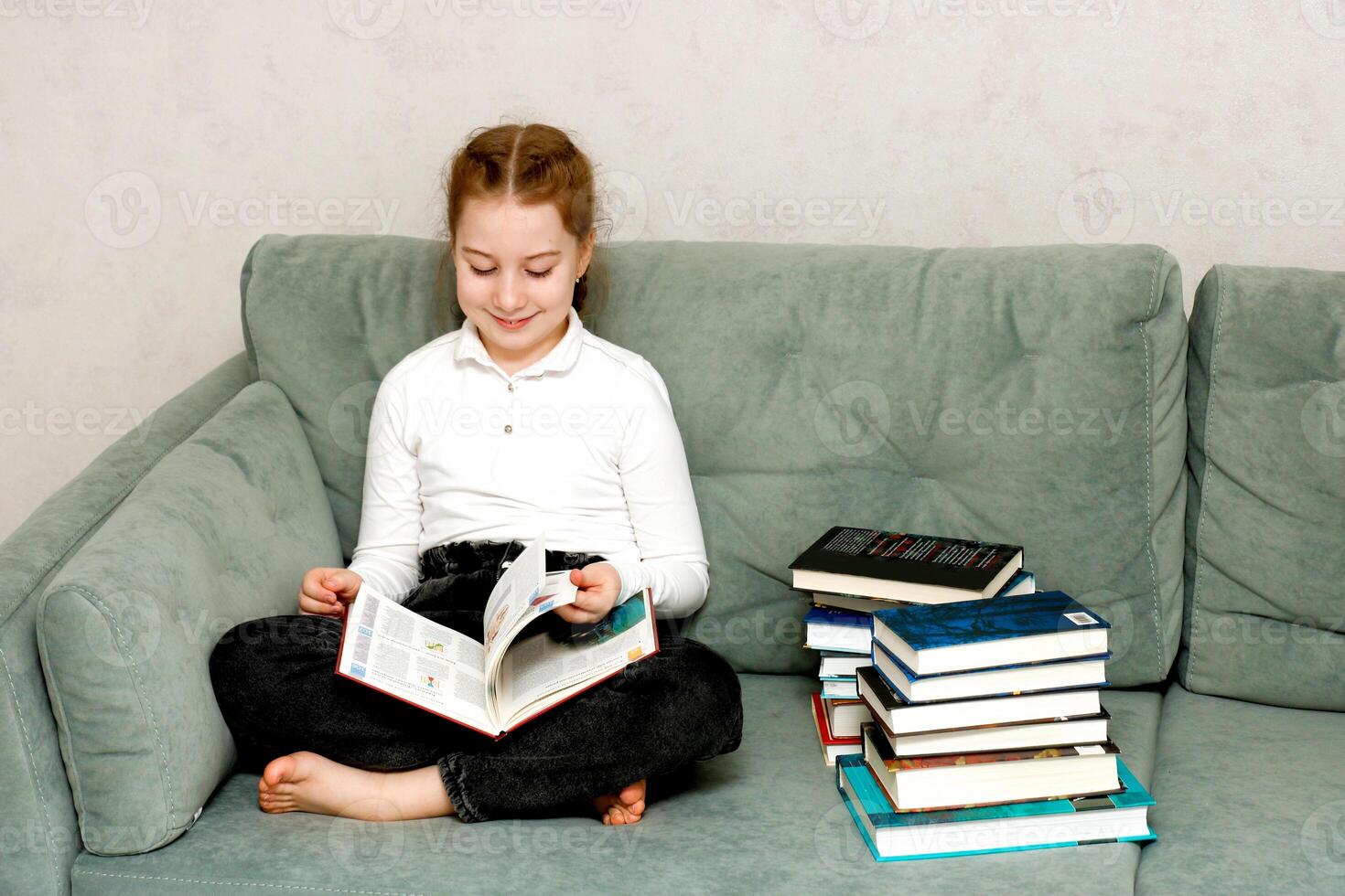 little girl reading a book sitting on the sofa photo