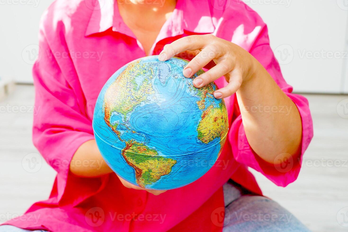 woman examines the globe she holds in her hands photo