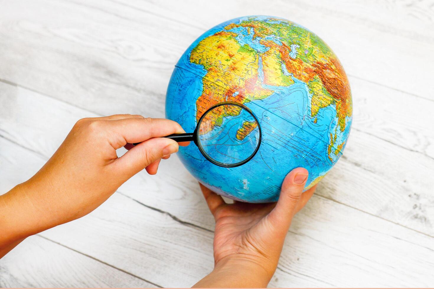 woman looking at Madagascar island on the globe through a magnifying glass photo