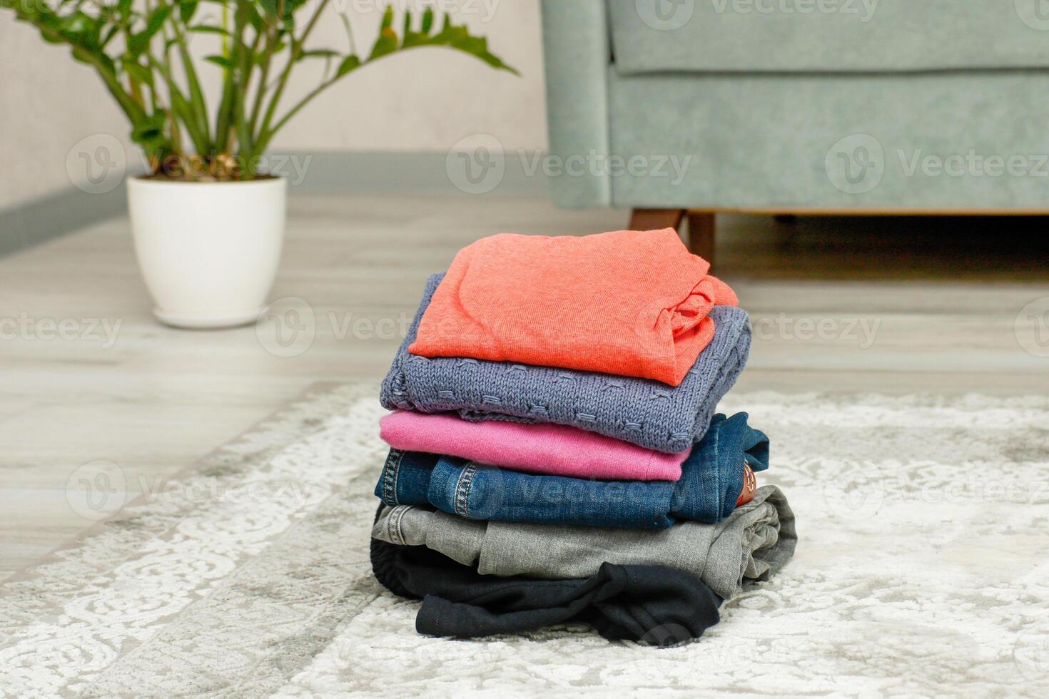 stack of folded clothes on the floor at home photo