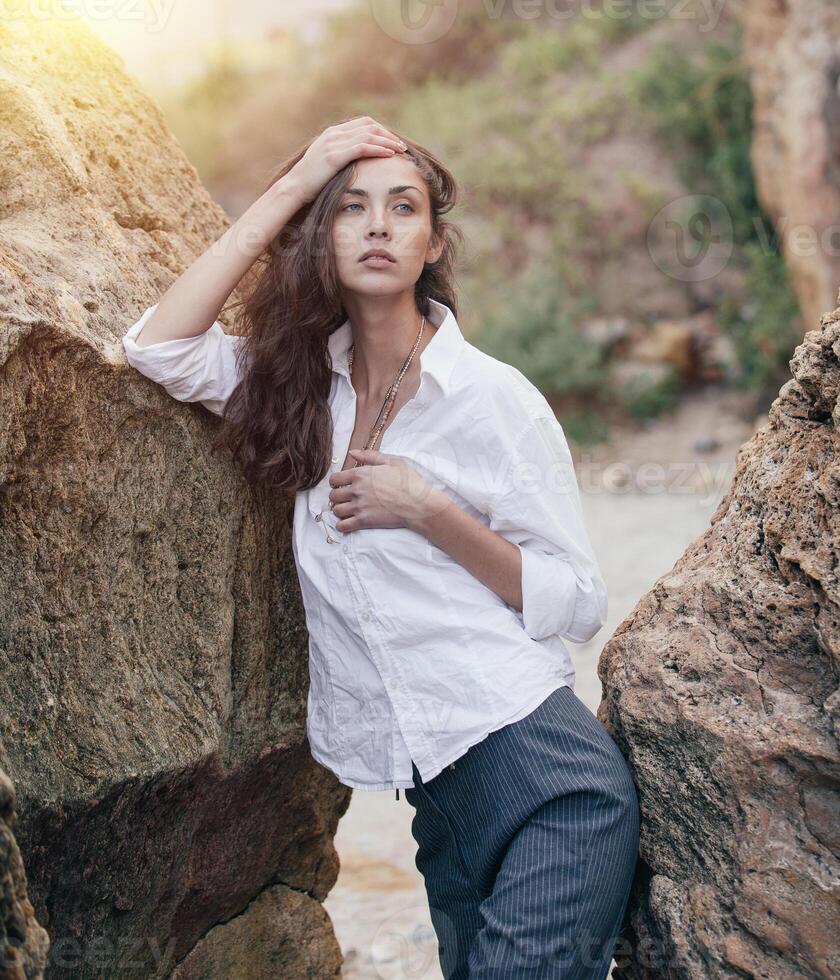 business woman on suit and white shirt standing near big stone on the sea cost photo