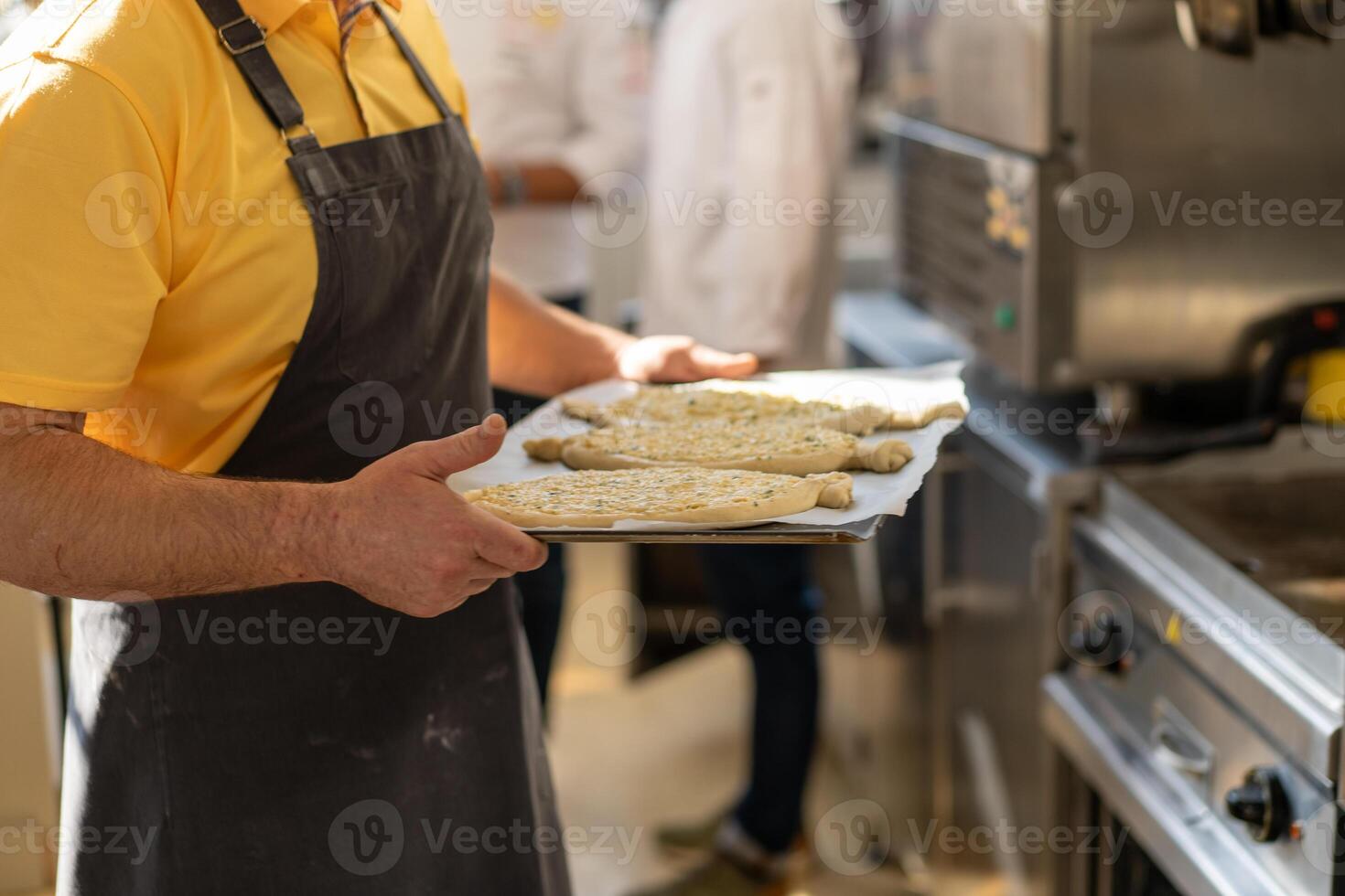 Closeup of male hands holding a tray with khachapuri, preparing to send to the oven. Traditional georgian cheese bread. Georgian food photo