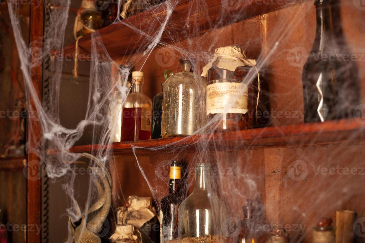 Halloween background Shelves with alchemy tools Skull spiderweb bottle with poison candles photo
