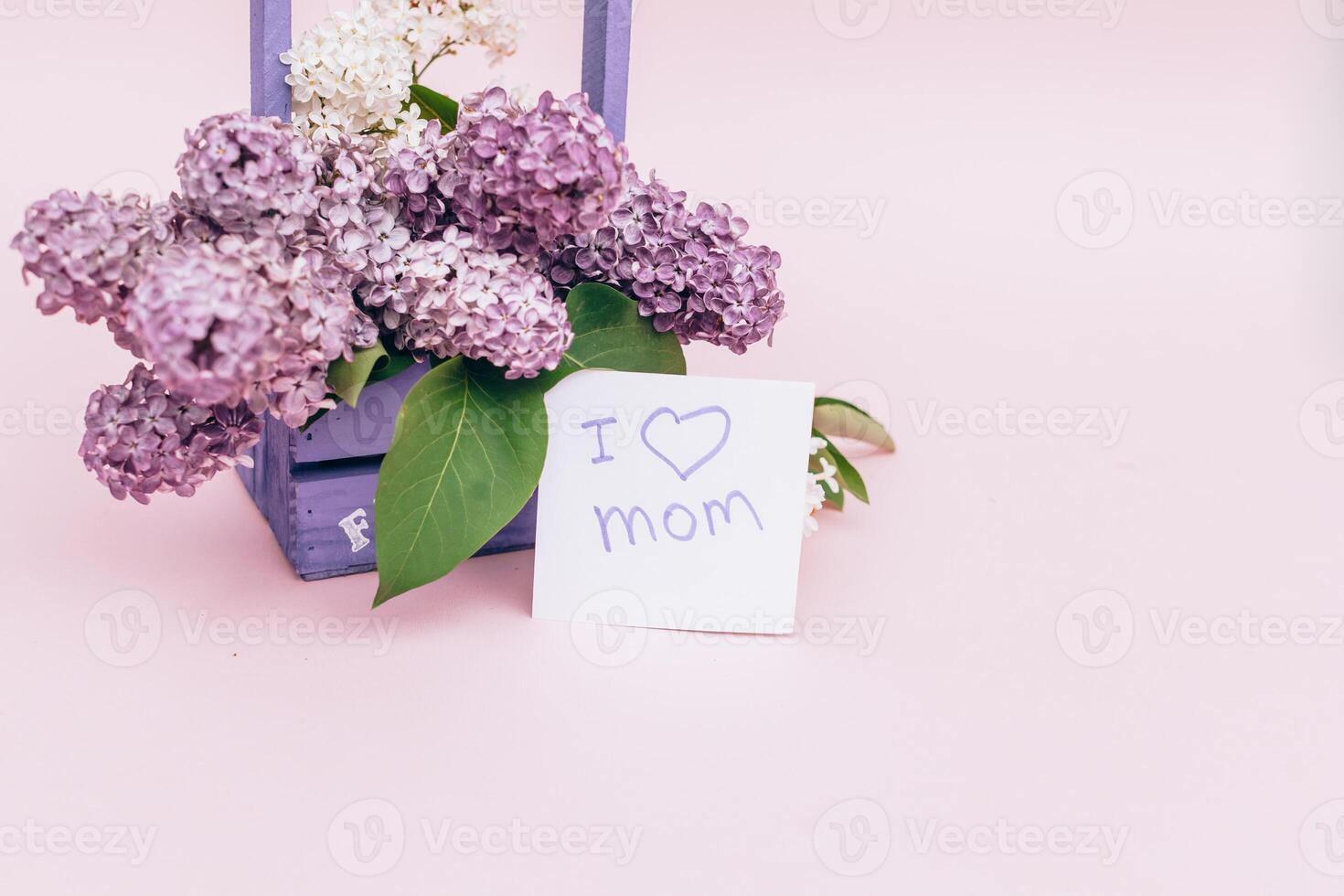 Beautiful bouquet of purple lilac and card on purple paper background photo