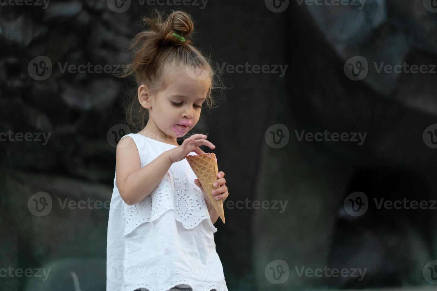 Little caucasian girl 3 years old eats ice cream closeup portrait photo