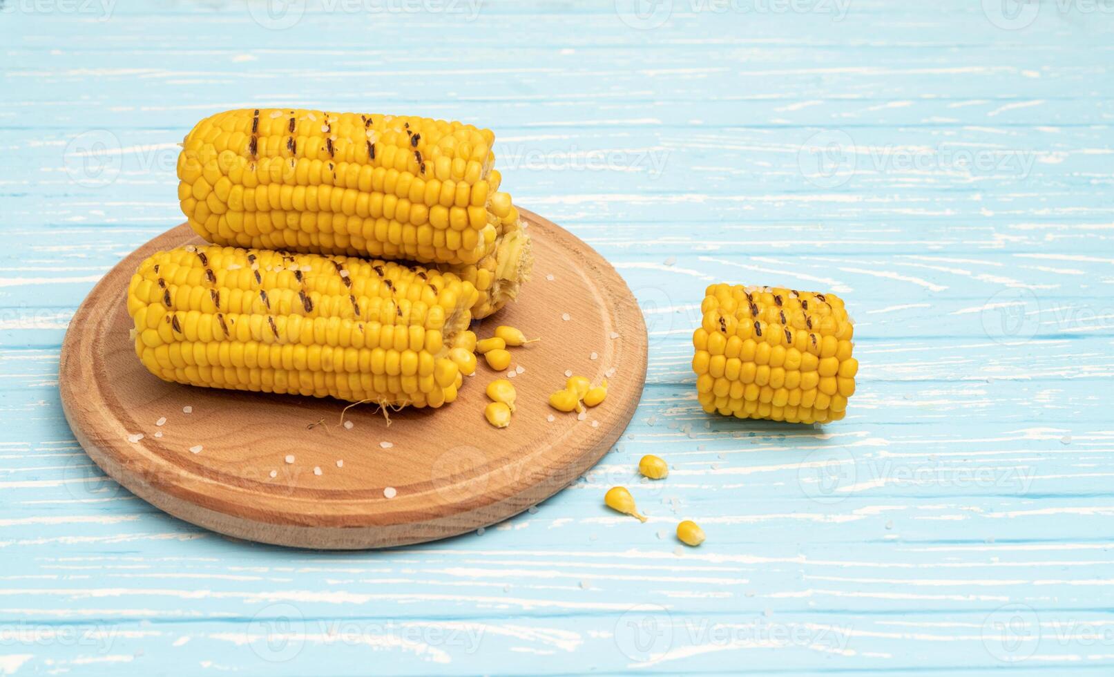 Grilled hot Corn cob lies on cutting board blue wooden table background. photo