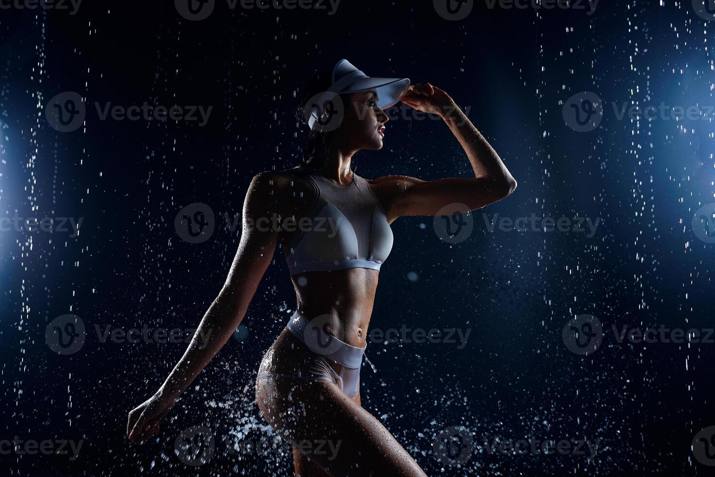 hermosa atlético caucásico niña con un Perfecto figura es en pie debajo el agua. aptitud mujer en un rociar de agua. Deportes frescura. concepto foto