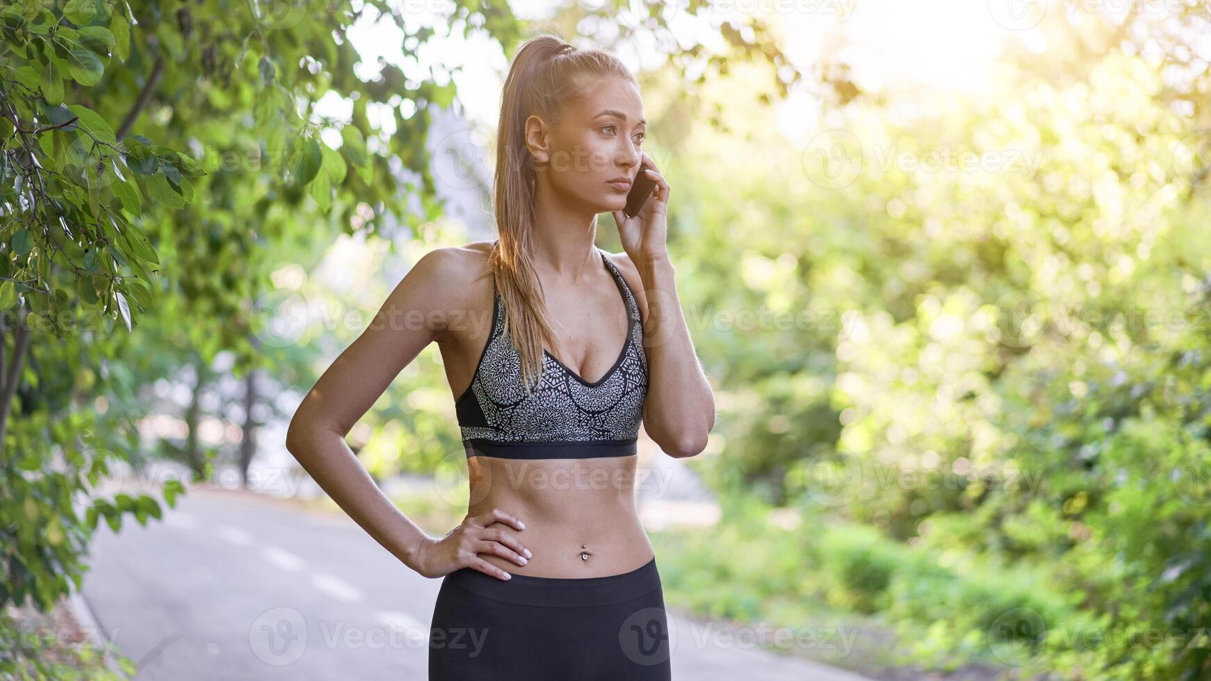 Woman runner standing before exercising summer park Talking on the phone. photo