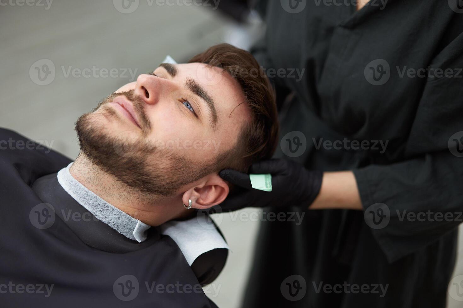 Young beautiful caucasian woman hairdresser cuts beard  handsome man at modern barbershop photo