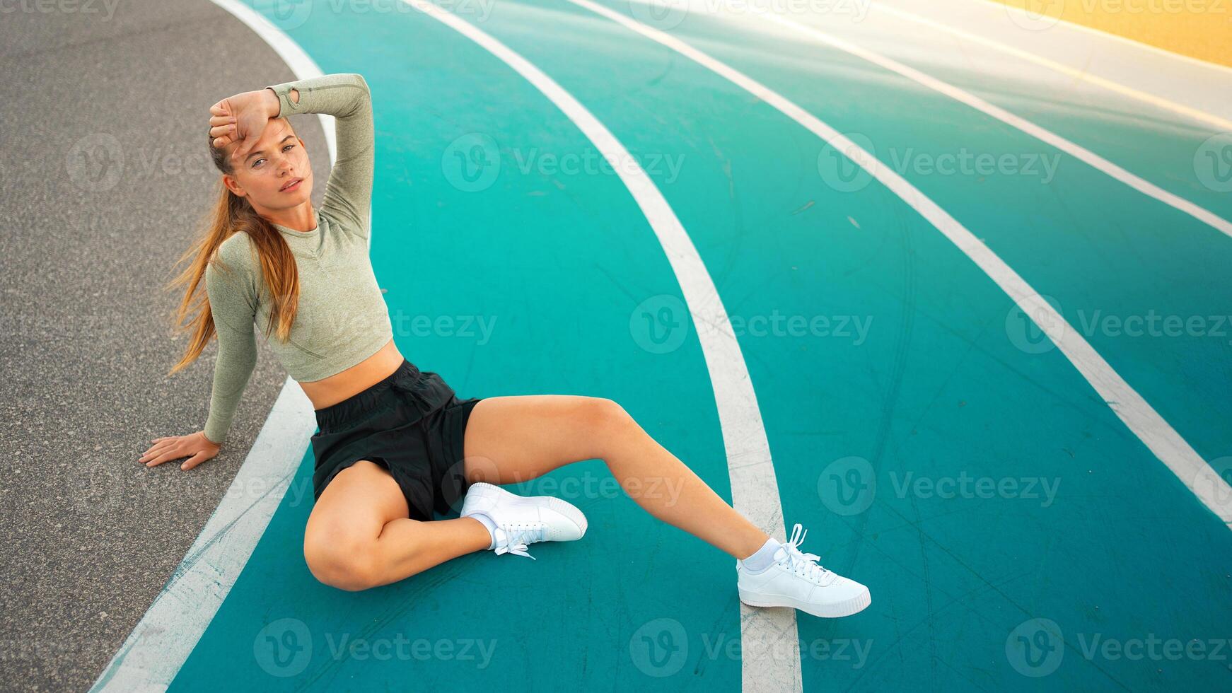 Tired happy woman runner taking rest after run sitting running track photo