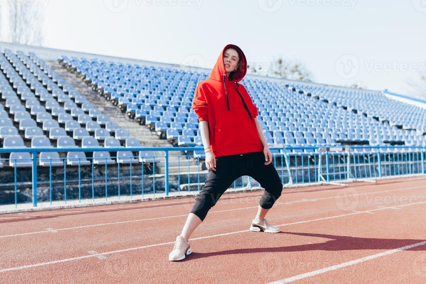 Beautiful girl in sportswear standing on the running track and preparing to run. Morning warm-up before exercise. photo