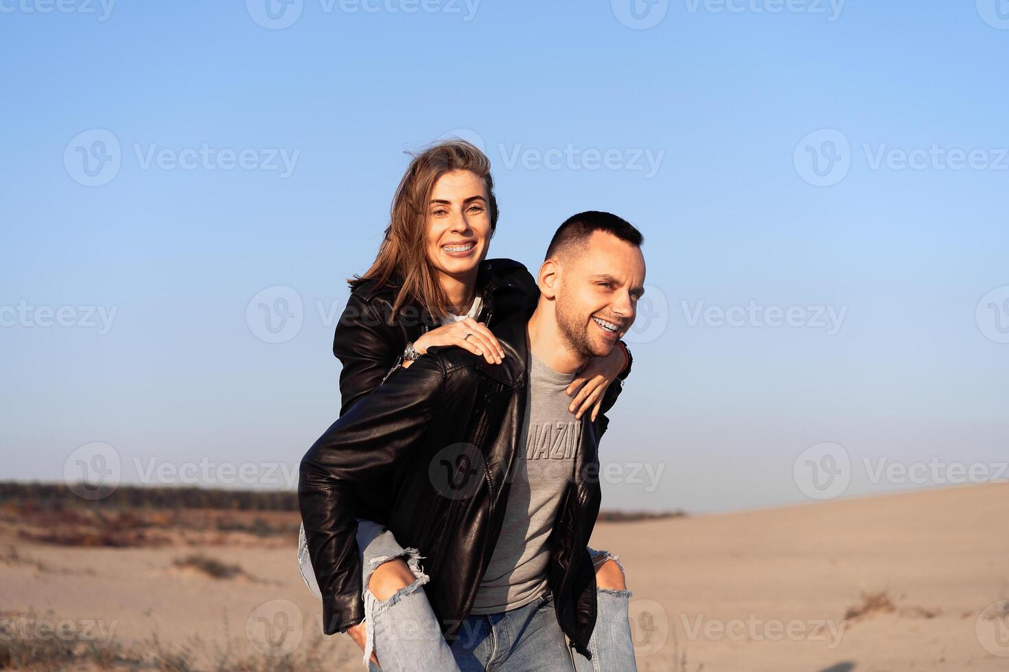 Happy and cute adorable adult couple of millennial hipsters, man with woman girlfriend on piggy back, have fun play photo