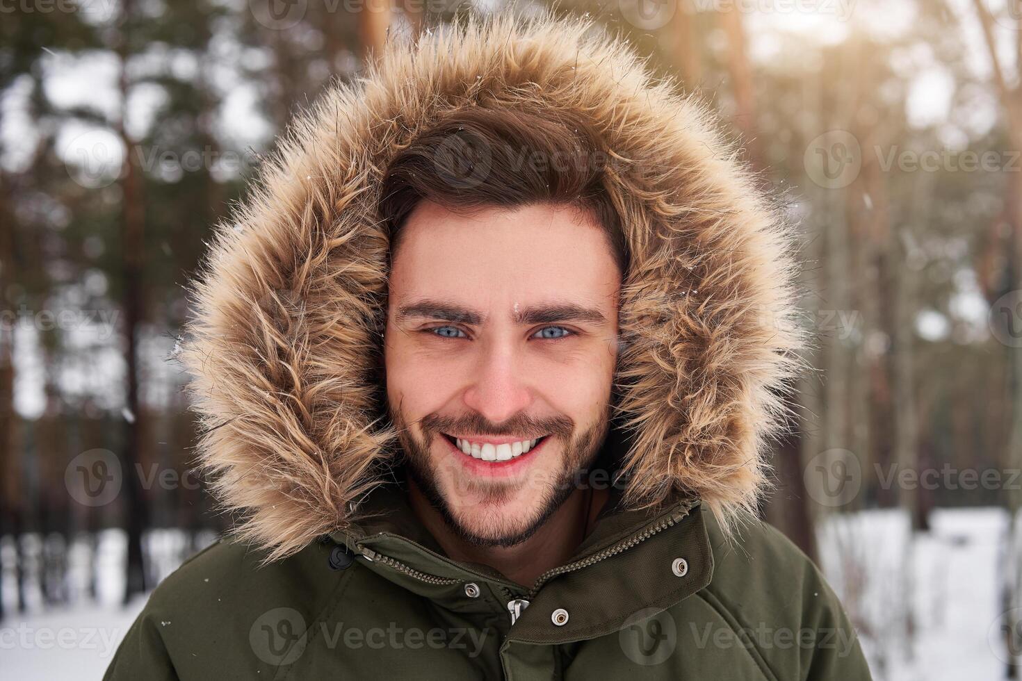 Attractive bearded man standing outdoors in winter season forest. photo
