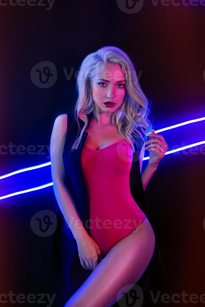 Fashion art photo of elegant model in seductive red swimsuit with light neon colored club spotlights Night club sexy concept