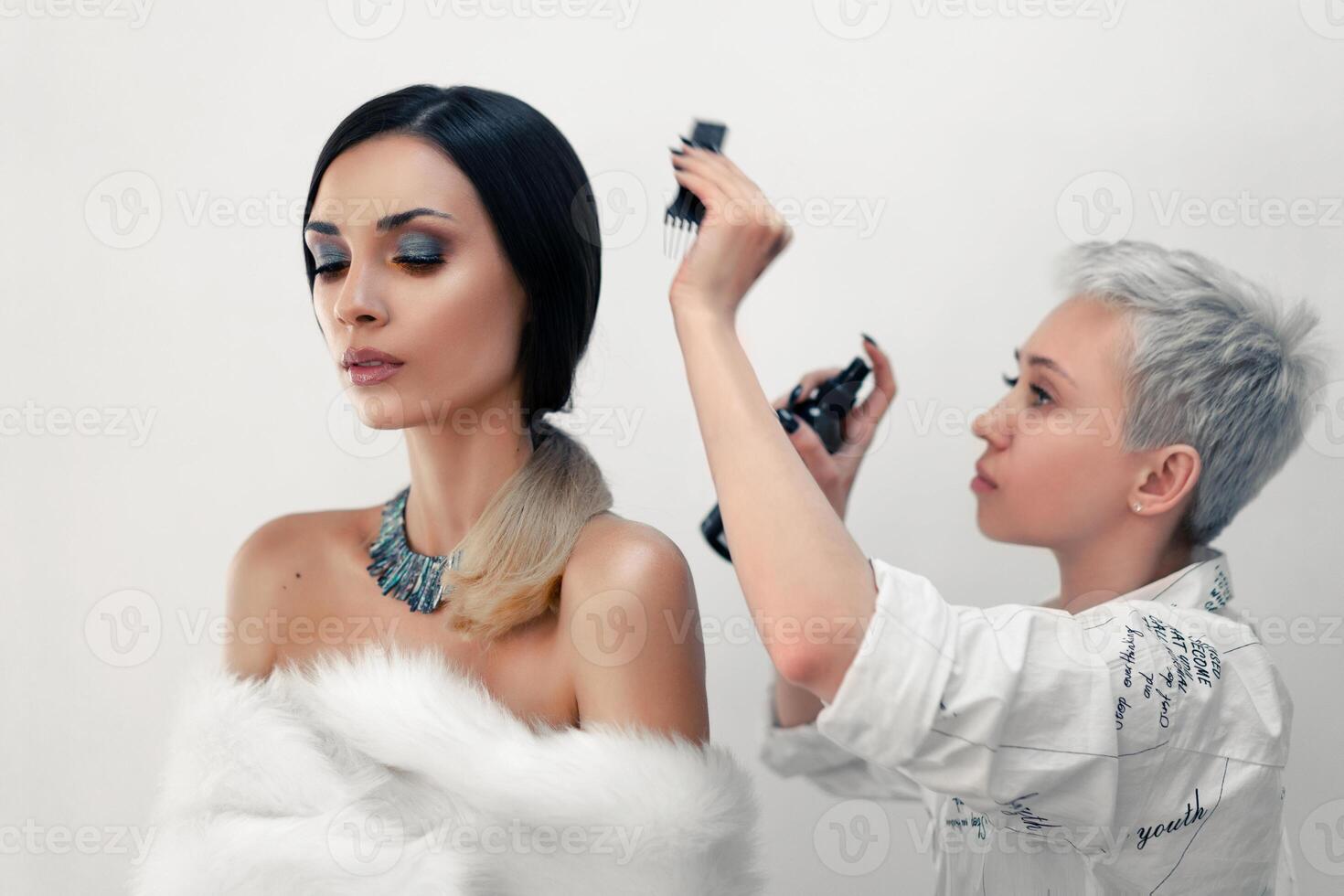 Hair stylist straightens hair beautiful model on the set during the break. photo