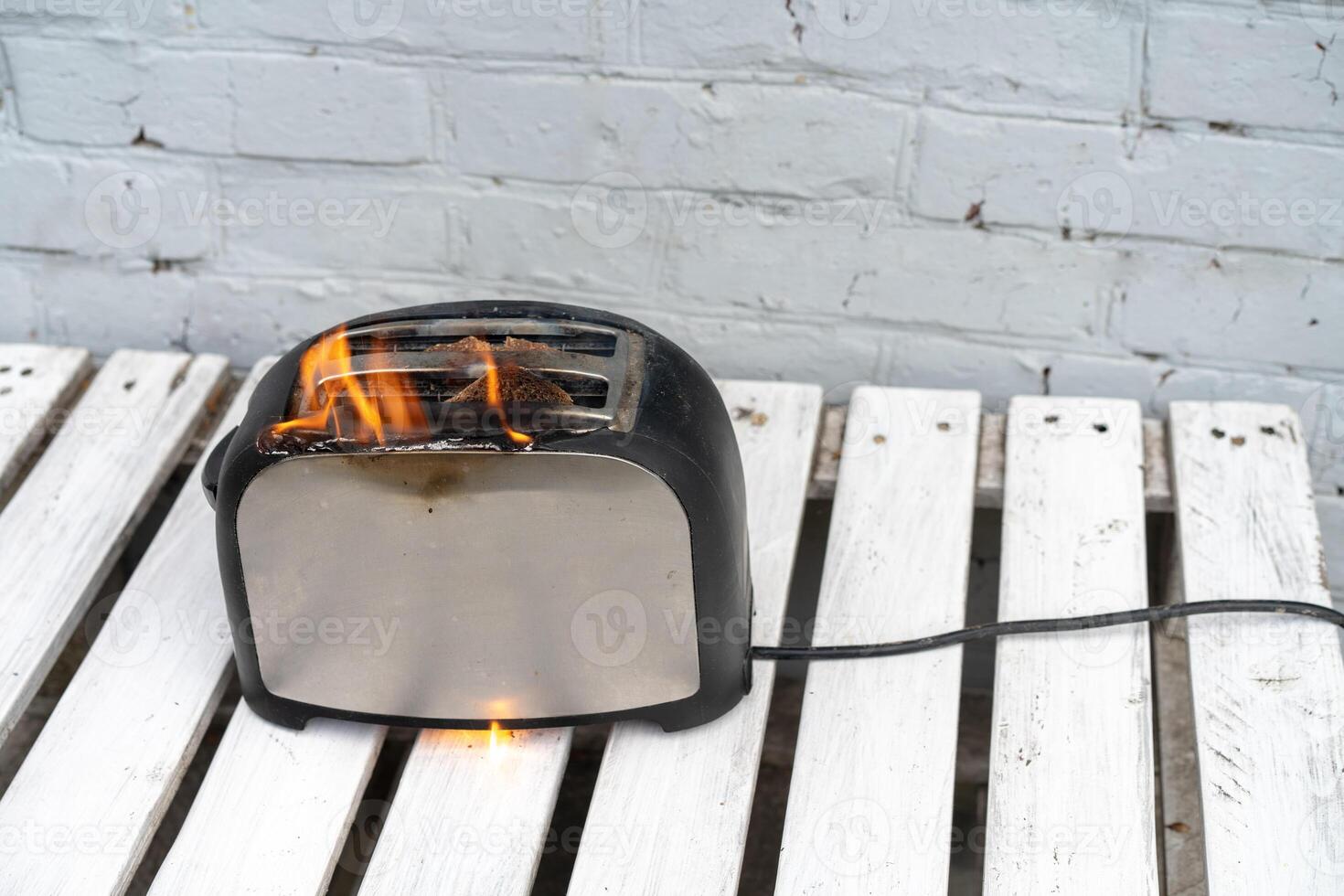 Burning toaster. Toaster with two slices of toast caught on fire over white background photo