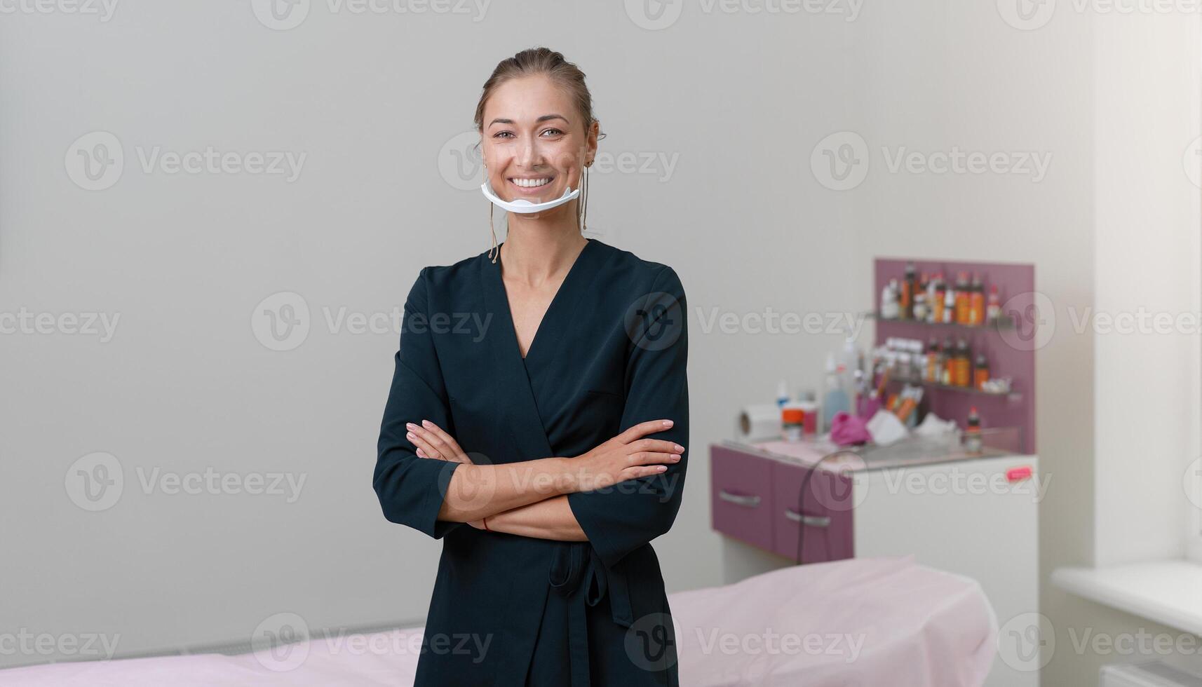 Cosmetology cabinet. Beautician stands in mask and smiles. photo