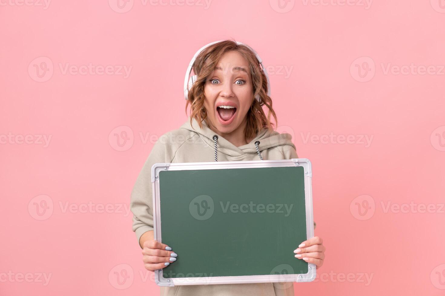 Woman holding empty chalkboard over pink background photo