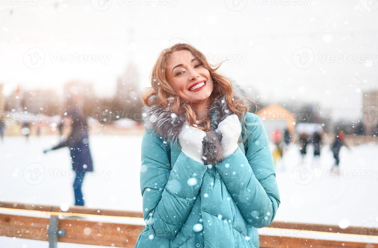 Beautiful lovely middle-aged girl with curly hair warm winter jackets stands ice rink background Town Square. photo