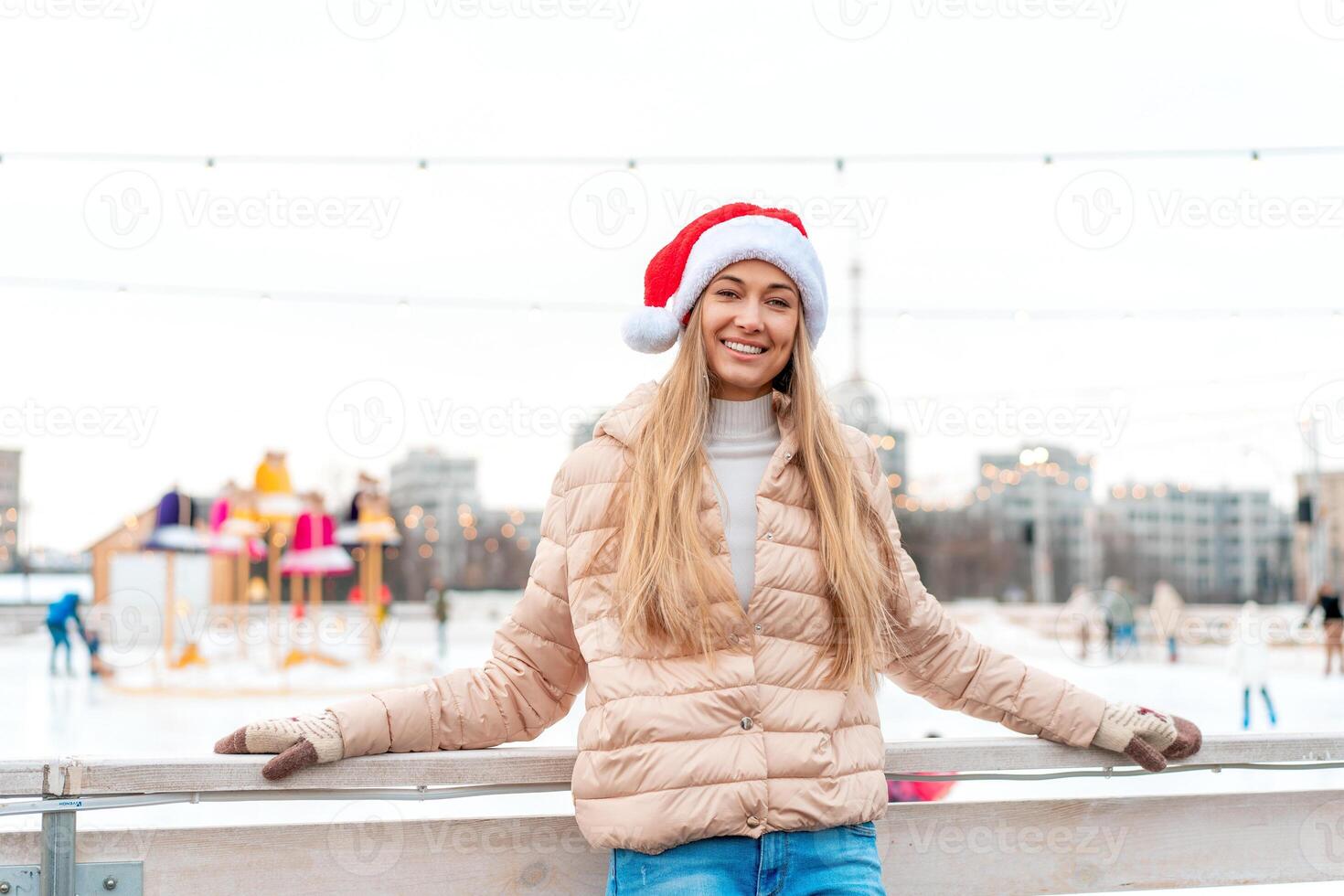 Outdoor portrait young beautiful fashionable woman wearing Santa hat, posing street of European city. Winter Christmas holidays concept. photo