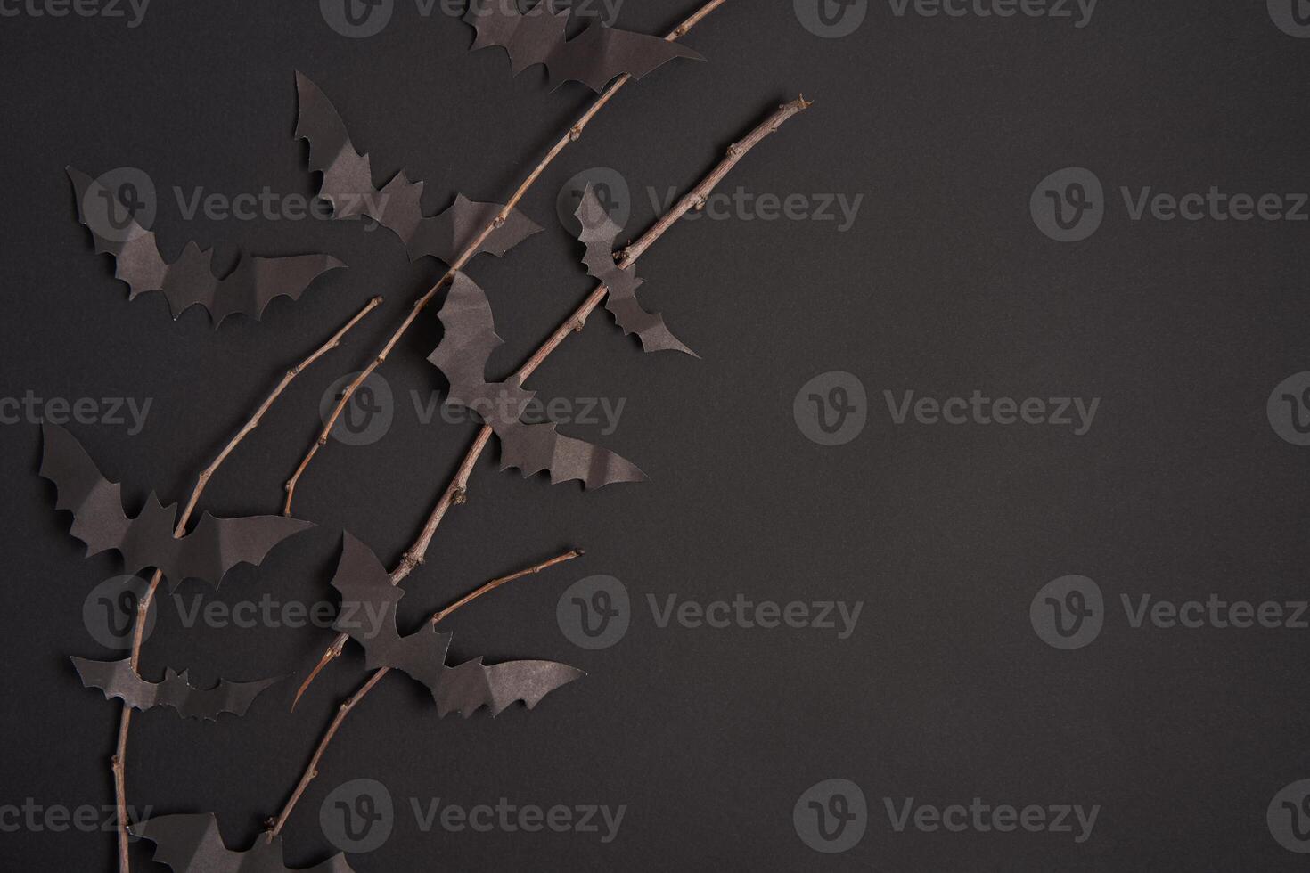 Halloween decoration concept black paper bats dry branch stick black cardboard background photo