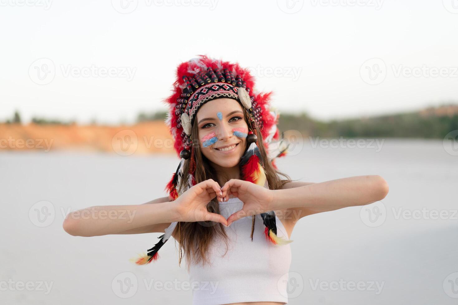 A beautiful young Caucasian girl in a white top on her head is wearing an Indian hat. Roach is in the desert. Happy holiday mood. photo