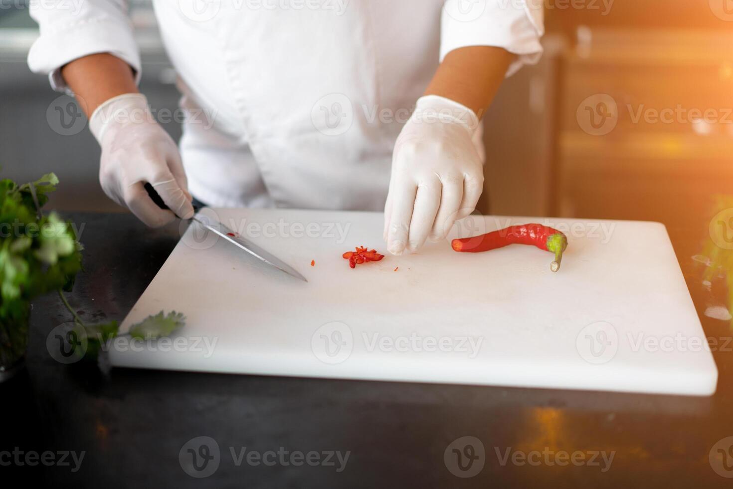 Unrecognizable young African chef standing in professional kitchen in restaurant preparing a meal of meat and cheese vegetables. photo