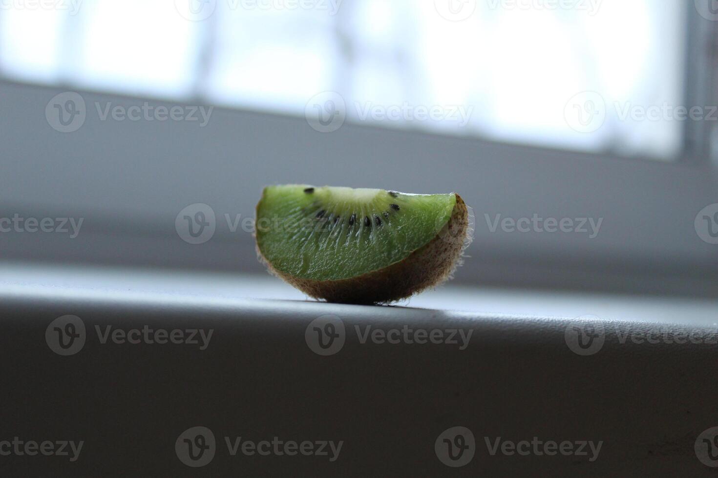 wedge slice of kiwi on a window sill white light background with a copyspace photo