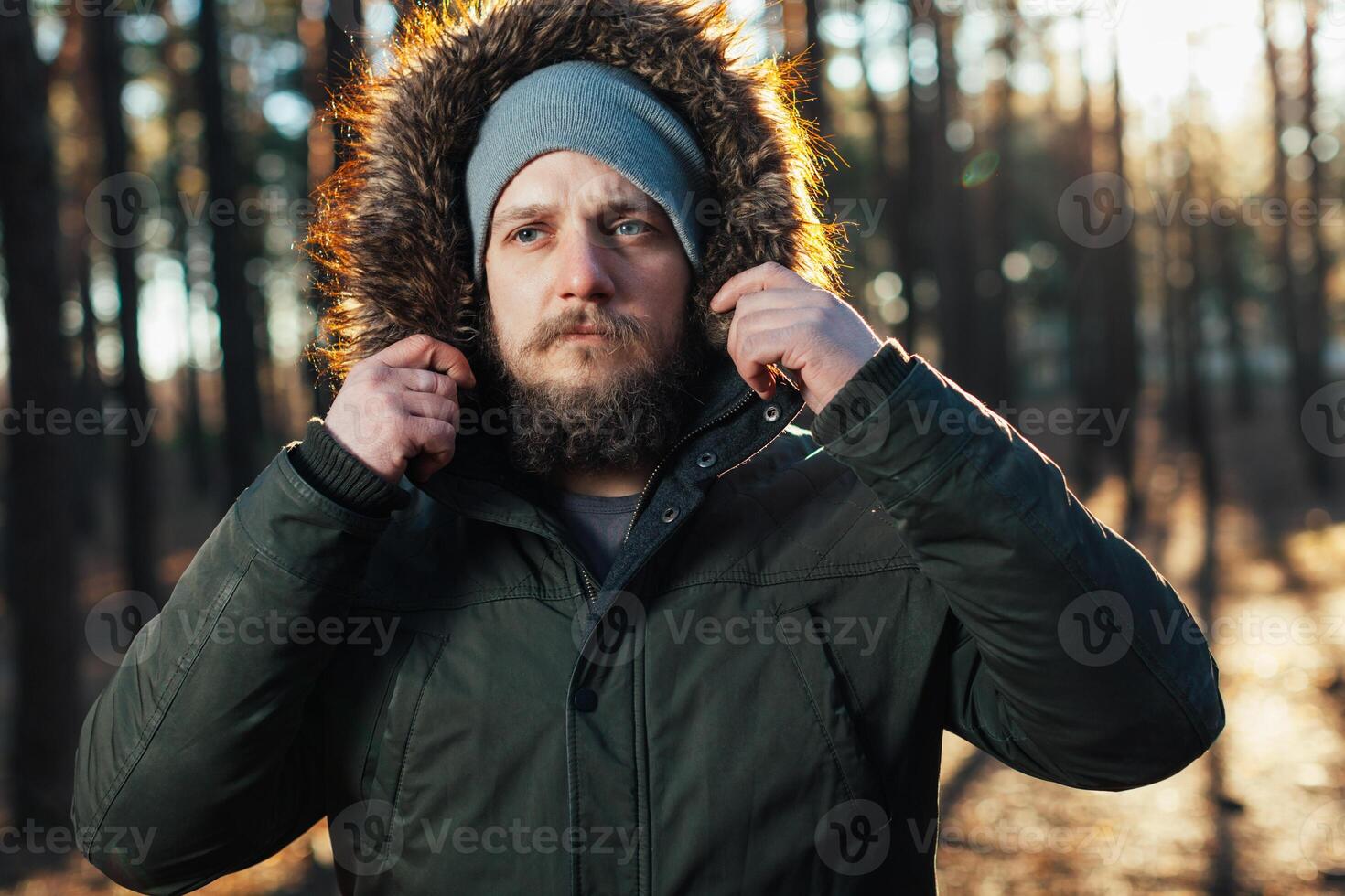 close up portrait of a bearded hipster tourist in gray hood man in the sunlight photo