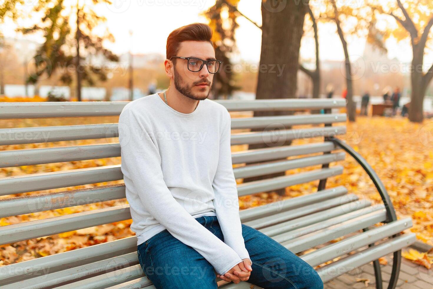 un solitario hermoso hombre se sienta triste en el parque en un banco. otoño estación, amarillo hojas en antecedentes. soledad concepto. el estudiante hizo no pasar el exámenes o rompió arriba con el niña foto