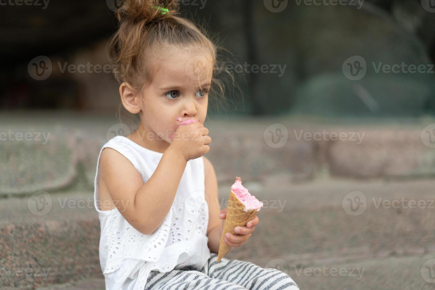 Little caucasian girl 3 years old eats ice cream closeup portrait photo