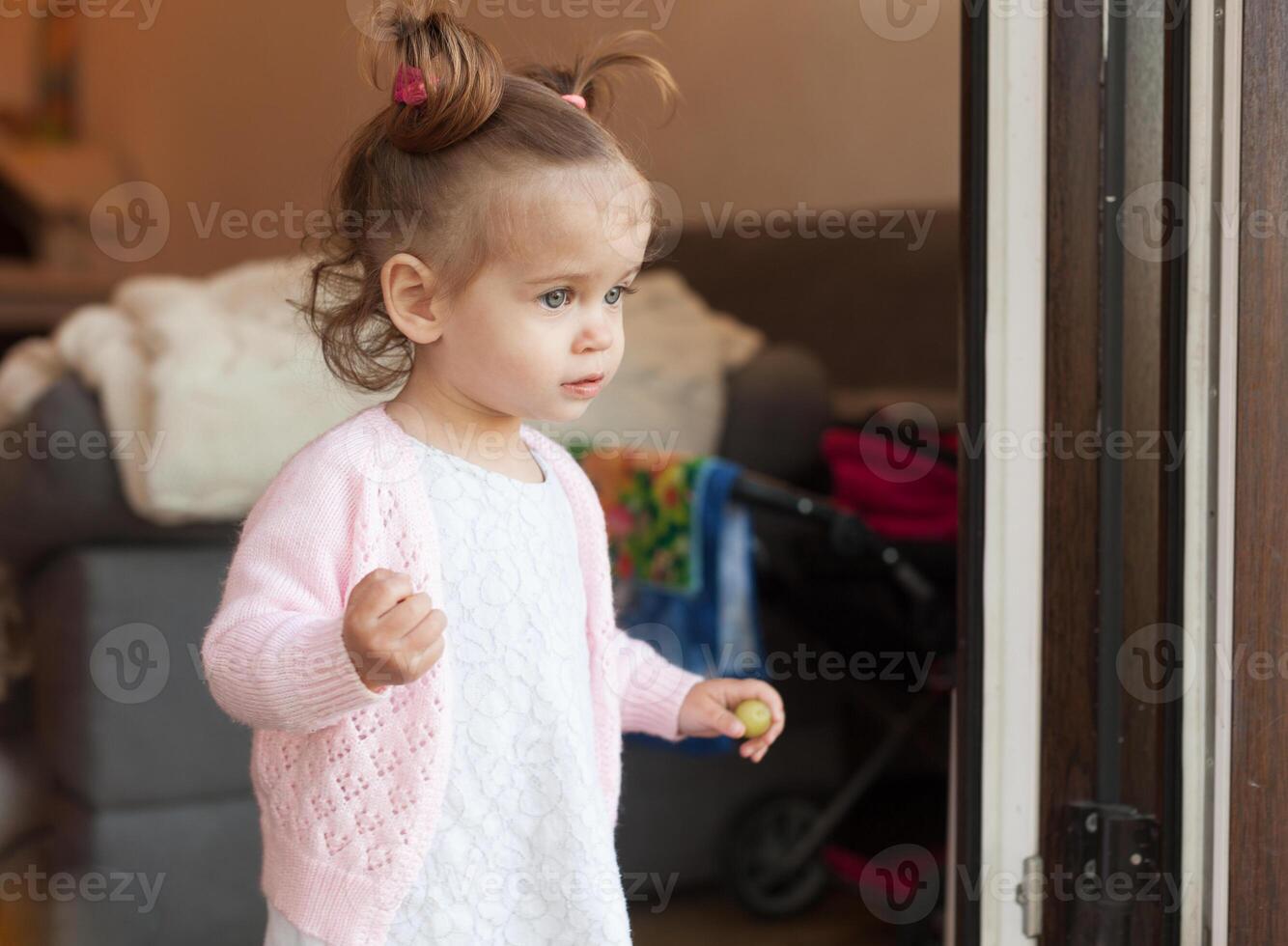 little curly girl a child coming out of the house is standing on the doorstep photo