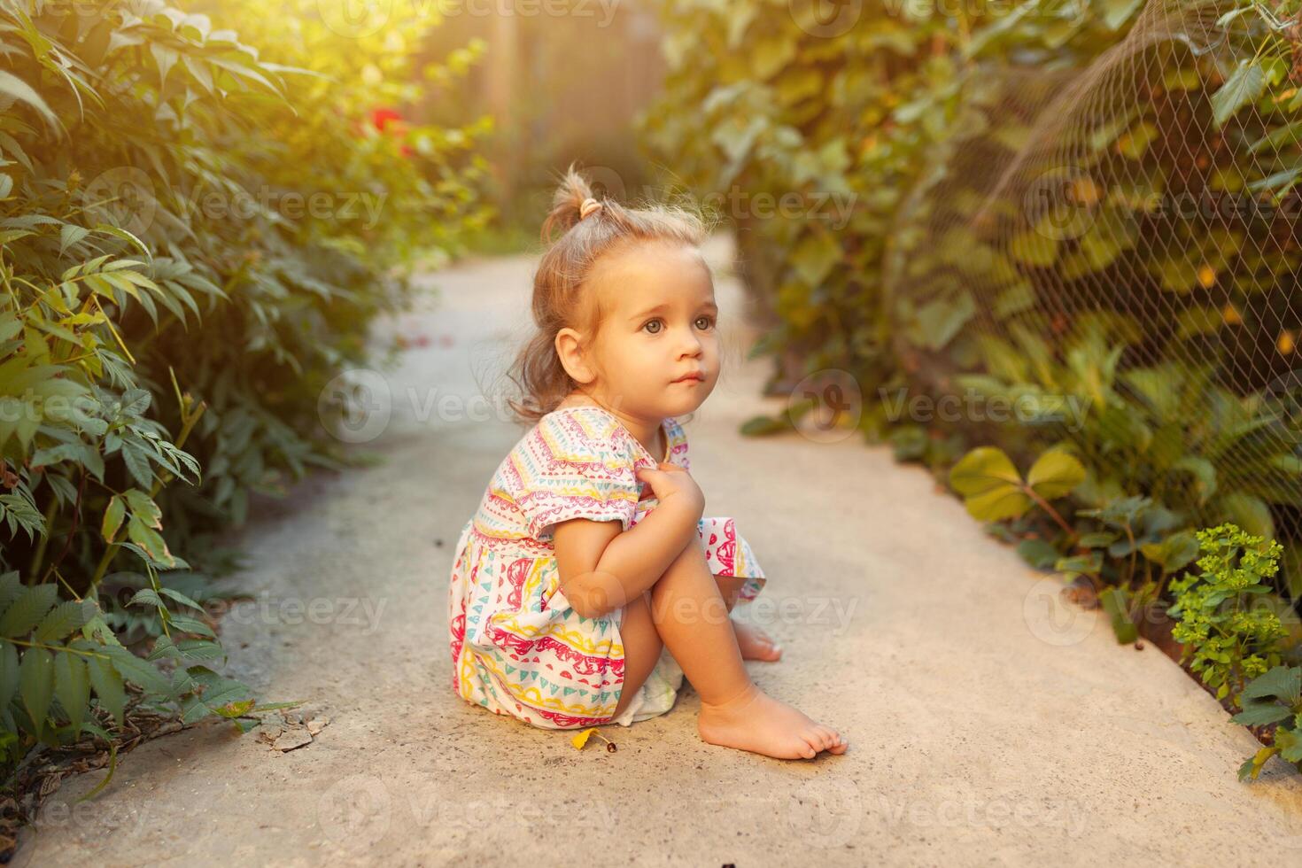 a little girl dressed in a fashionable dress strolls in the backyard or in the park on a warm summer sunny afternoon, summer vacation concept photo