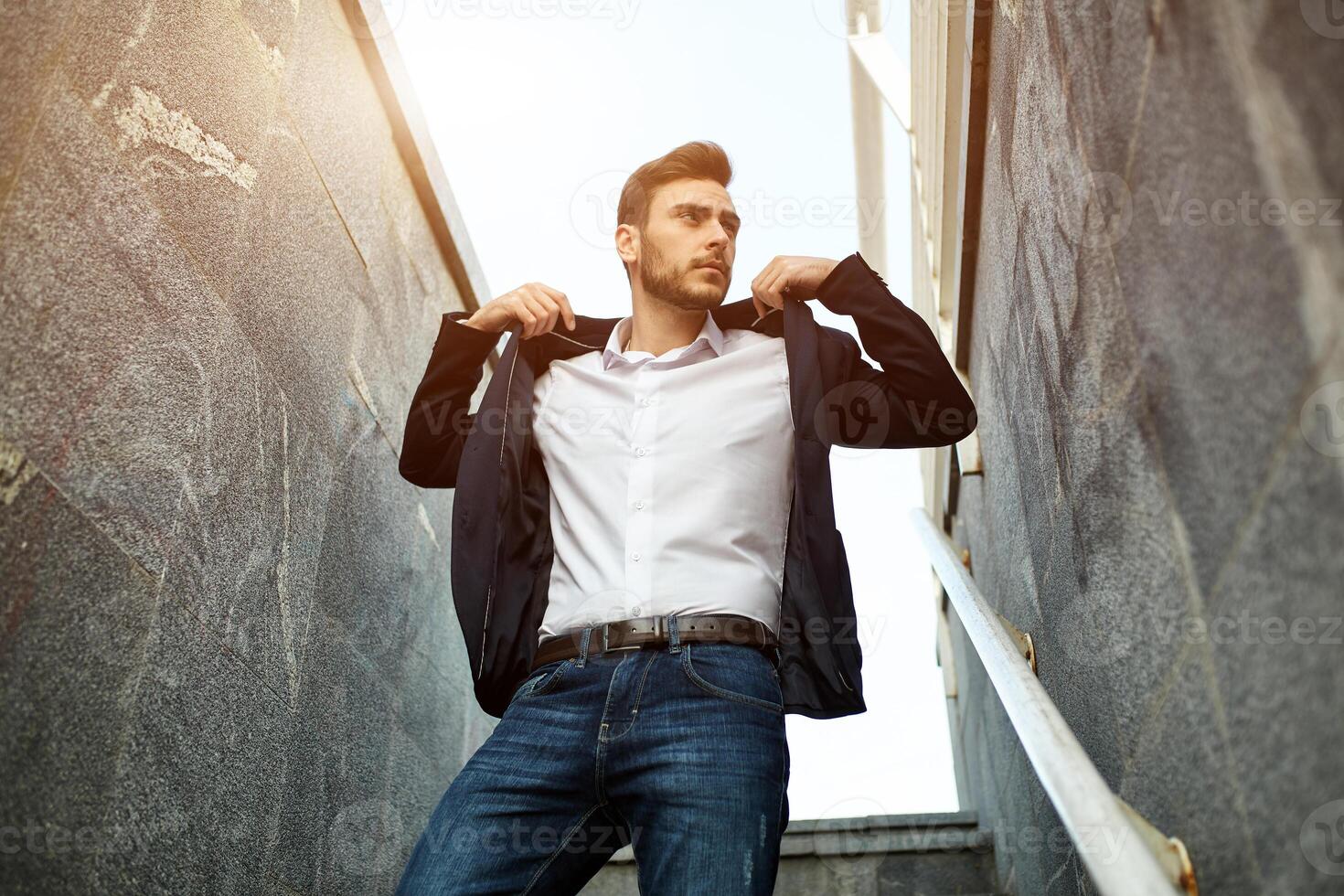 Elegant and fashionable businessman in jacket standing on the stairs classical architecture building. photo