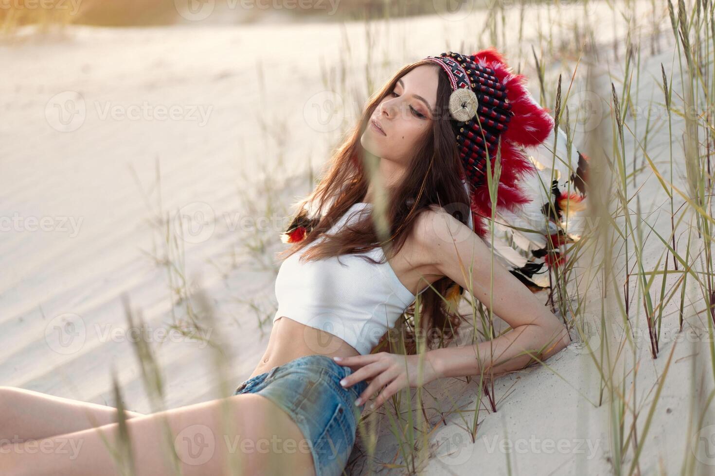 un hermosa joven caucásico niña en un blanco parte superior en su cabeza es vistiendo un indio sombrero. cucaracha es en el desierto. contento fiesta humor. foto