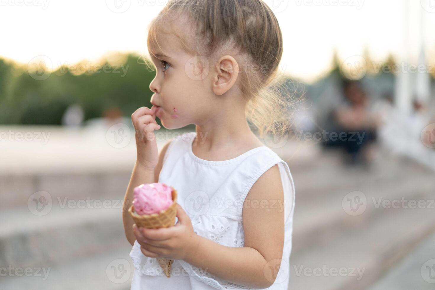 Little caucasian girl 3 years old eats ice cream closeup portrait photo