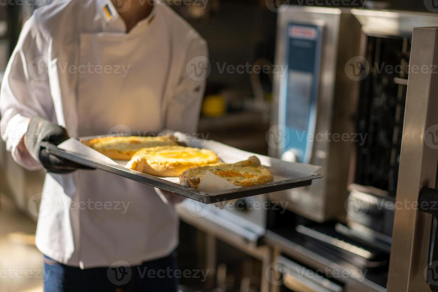 Closeup of male hands holding a tray with khachapuri, preparing to send to the oven. Traditional georgian cheese bread. photo