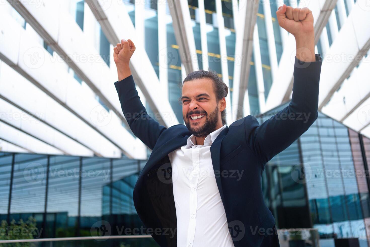 emocionado joven empresario en traje celebrando victoria brazos elevado foto