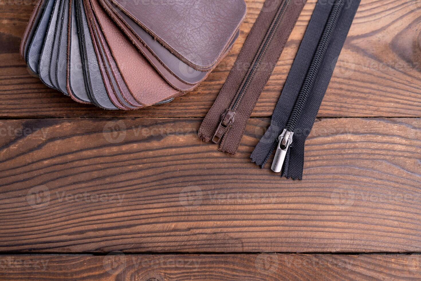 Leather samples for shoes and zipper on dark wooden table. photo