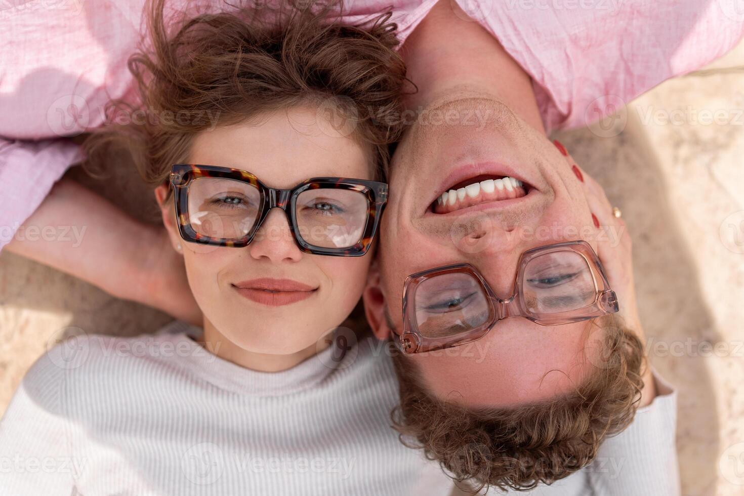 Two attractive students wearing stylish glasses lying on the floor photo