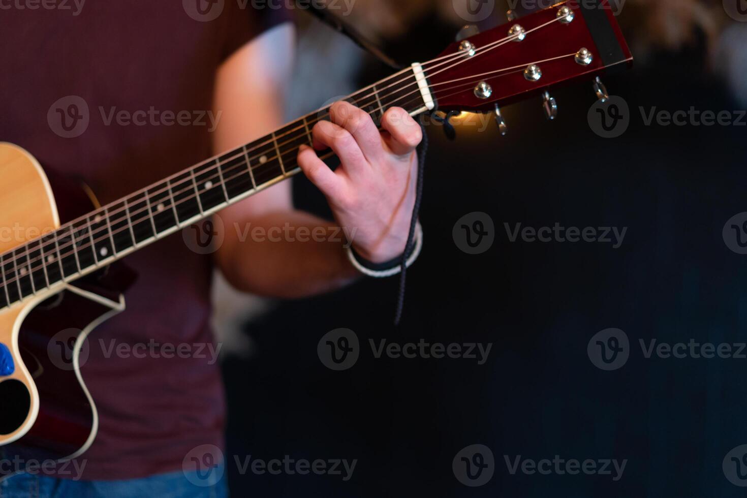 Male musician playing acoustic guitar. Guitarist plays classical guitar on stage in concert Close up photo