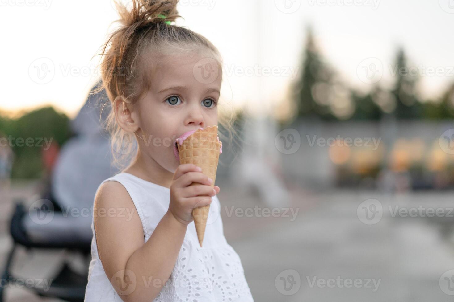 Little caucasian girl 3 years old eats ice cream closeup portrait photo