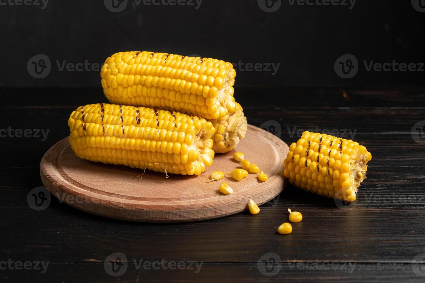 Grilled hot Corn cob lies on cutting board wooden table background. photo