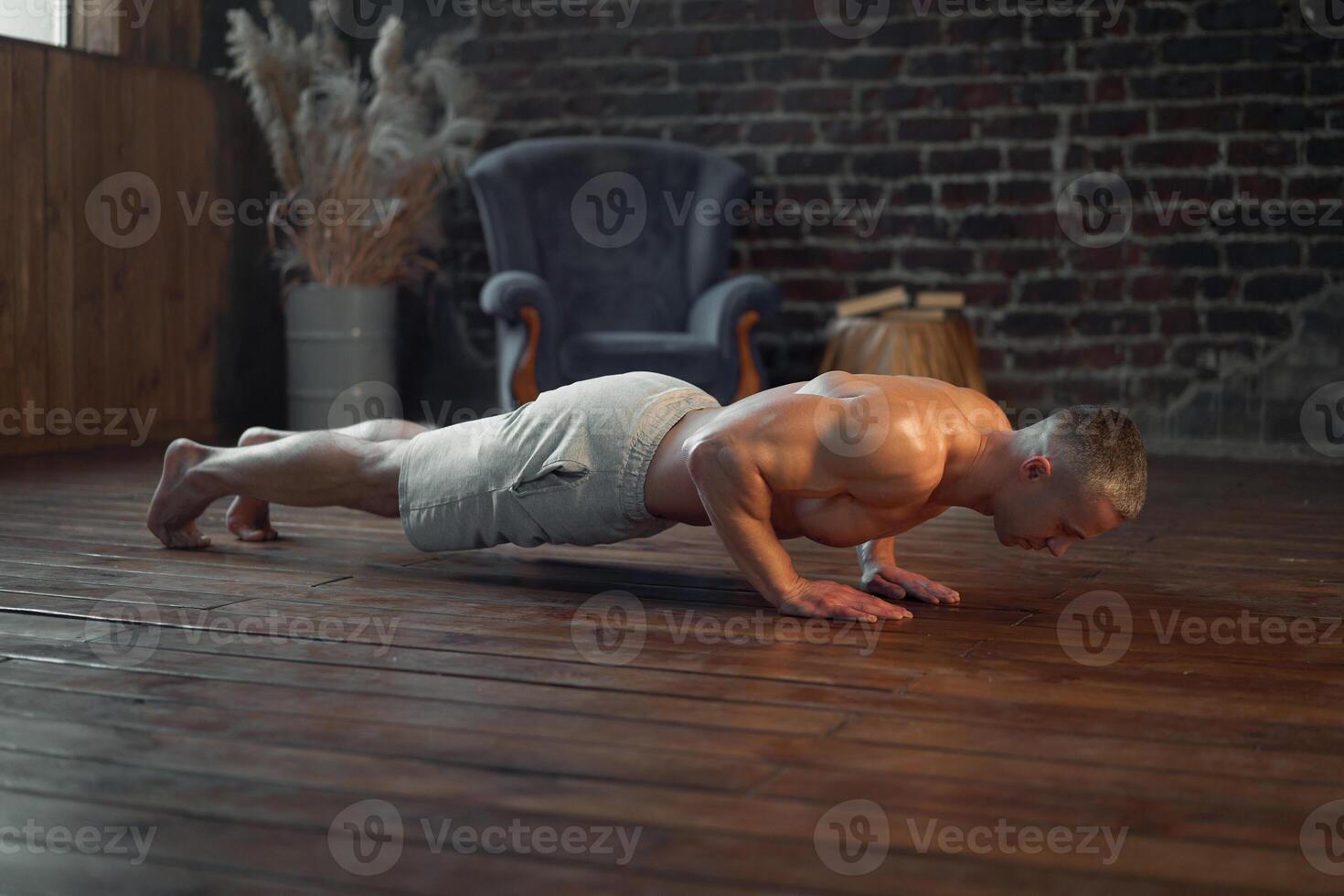 Endurance workout. Muscular man practicing push ups exercise at home interior photo