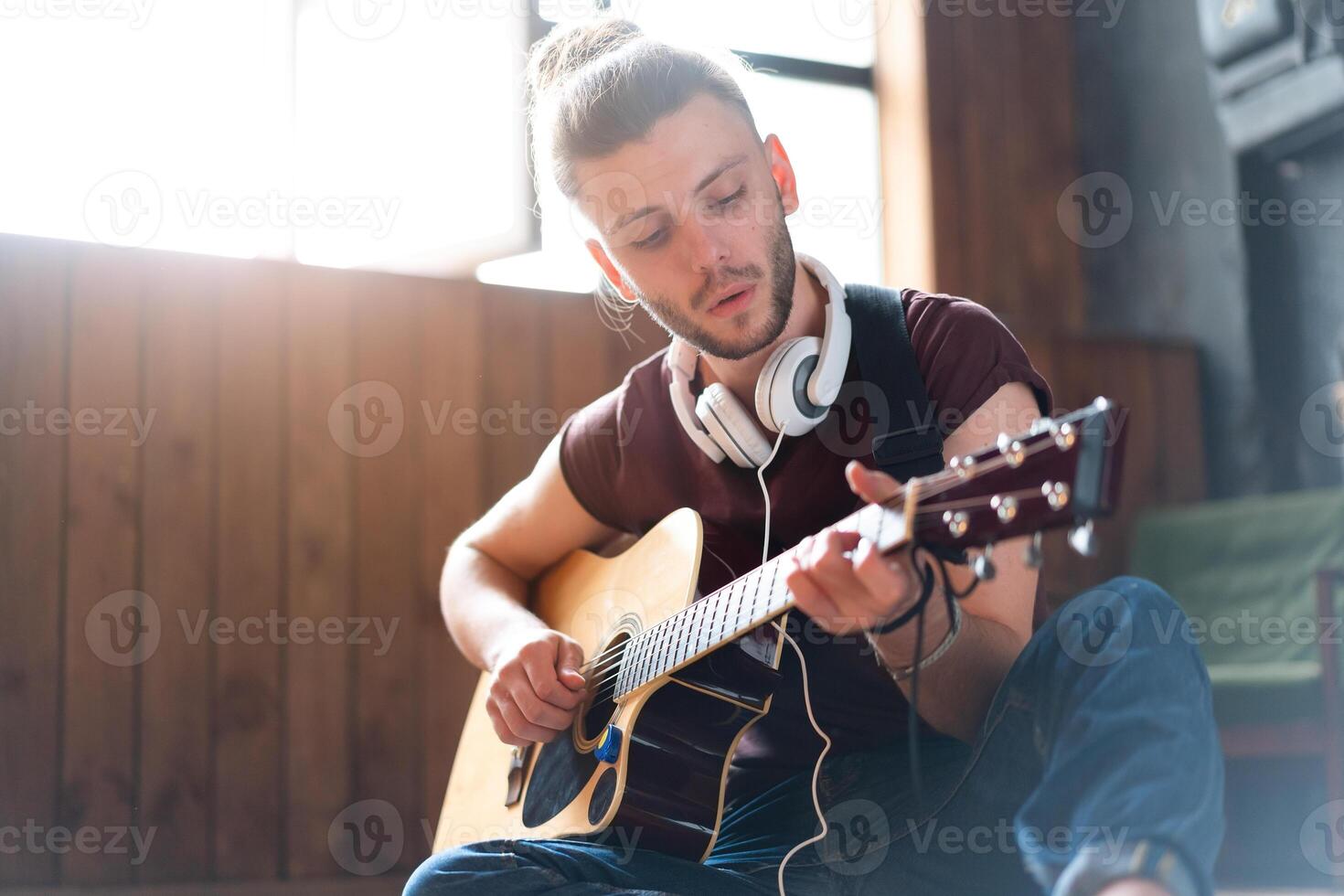 hermoso joven hombre jugando acústico guitarra sentado piso vivo desván habitación foto